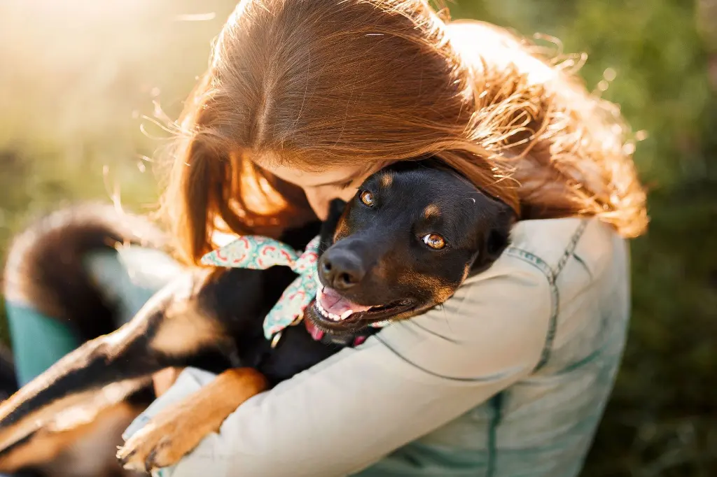 woman holding a black and brown dog